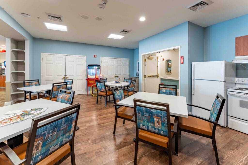 MM_Patti-Hanna_001 - Inspirations of River Centre An interior room for socializing. The room includes multiple tables, comfortable chairs, and a shared community kitchen.