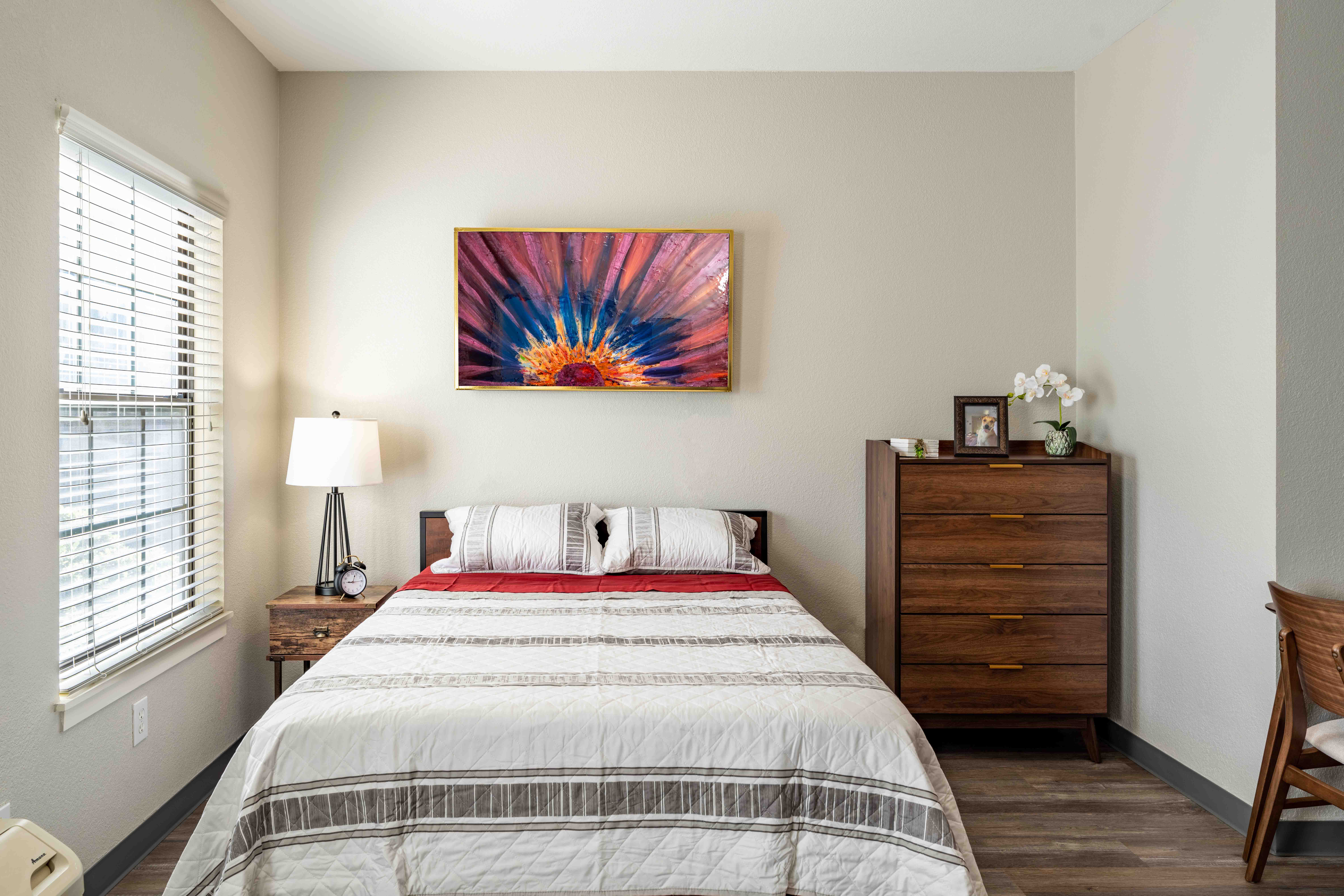 Interior shot of a resident's studio bedroom with comfortable furniture and colorful artwork.