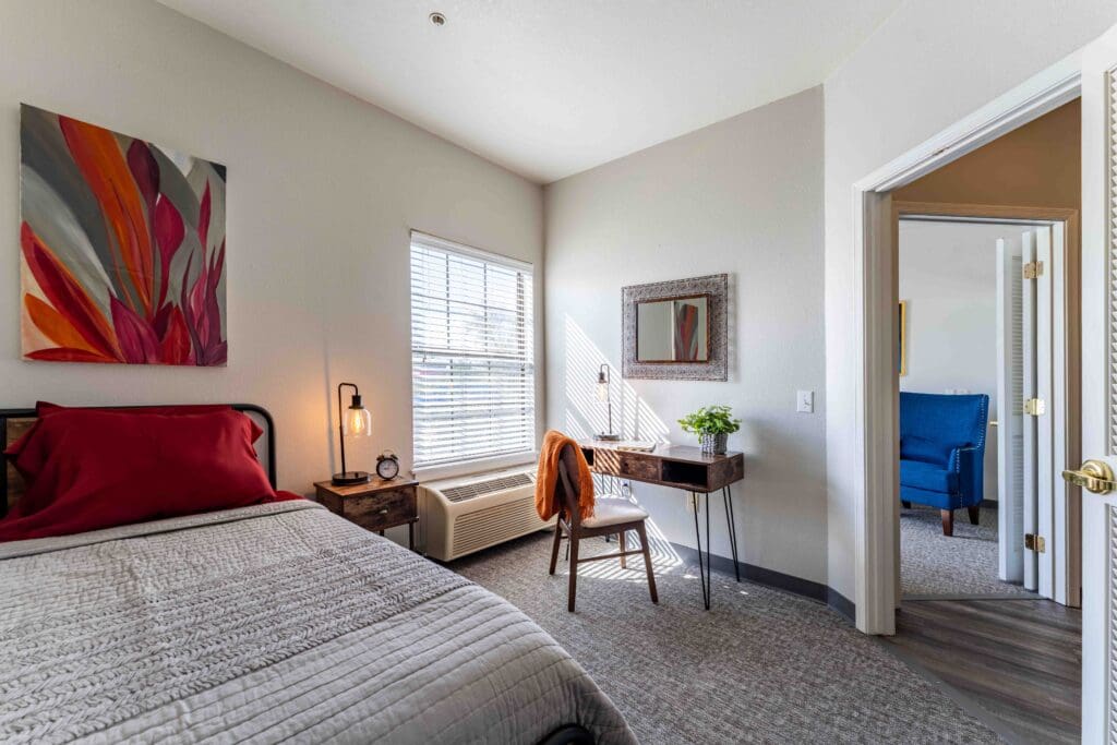 MM_Patti-Hanna_028 - Inspirations of River Centre Interior shot of a resident's bedroom. A bed, side table, and small desk decorate the room.